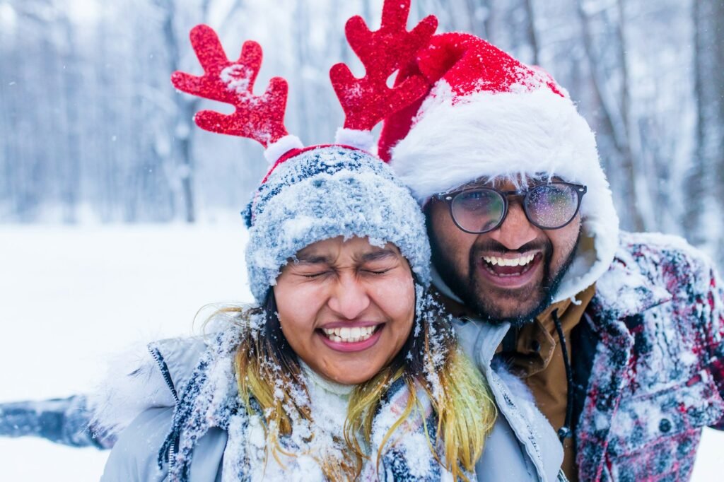 portrain of indian man and woman in red santa hat and deer horns with throwing snow on face