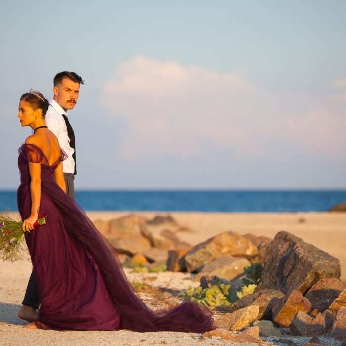 The wedding day at the sea. Young romantic couple relaxing on the beach watching the sunset